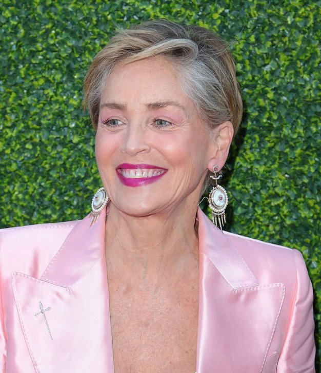 Igralka Sharon Stone blesti v roza satenastem kostimu in belih športnih copatih, ko se pridruži igralcu Seanu Pennu na zvezdniški …
