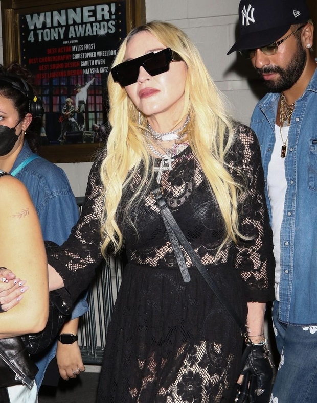 Madonna je nosila dolgo, prosojno črno čipkasto obleko, ki je razkrivala črn modrček in enake kratke hlače z visokim pasom. …
