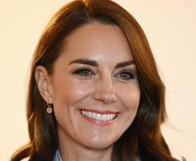 Kate Middleton nosila pepelkino različico poslovnega videza z bluzo s pentljo, dolgim plaščem in modrimi hlačami