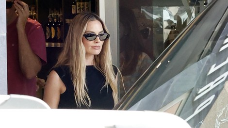 Materinski sijaj Margot Robbie: na plaži navdušila v elegantni črni obleki